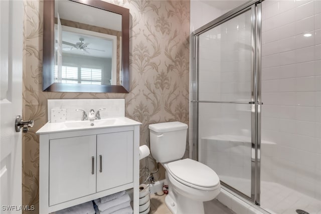 bathroom featuring vanity, a shower with shower door, toilet, and ceiling fan