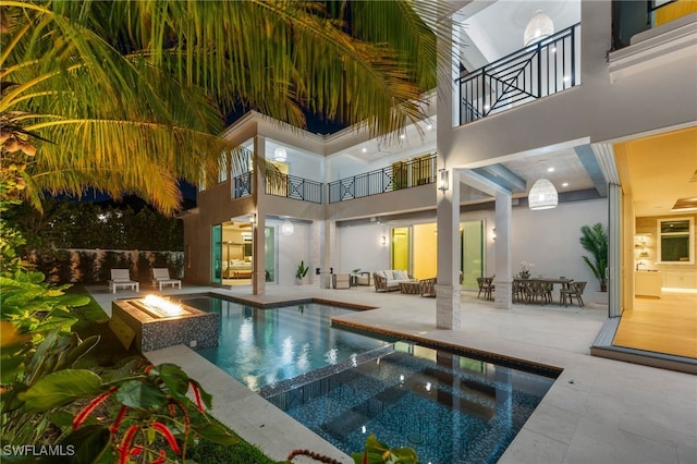 view of swimming pool featuring an in ground hot tub, an outdoor living space with a fire pit, and a patio