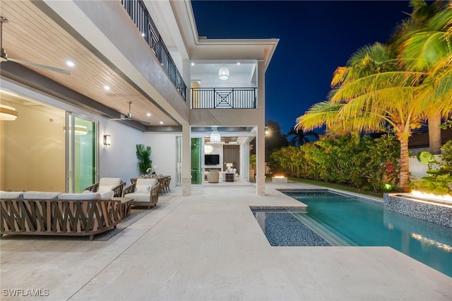 pool at night with a patio and an outdoor hangout area