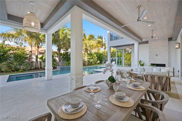 exterior space with ceiling fan, a large fireplace, a swimming pool, and wood ceiling