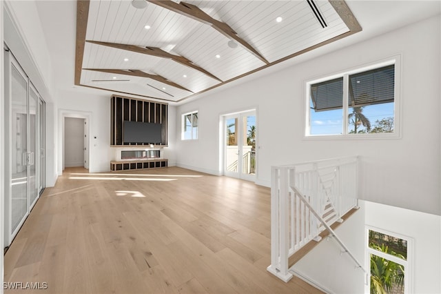 unfurnished living room with wooden ceiling, plenty of natural light, lofted ceiling with beams, and light wood-type flooring