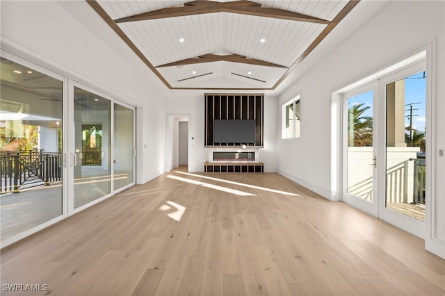 unfurnished living room with french doors, lofted ceiling with beams, a fireplace, wood ceiling, and light wood-type flooring