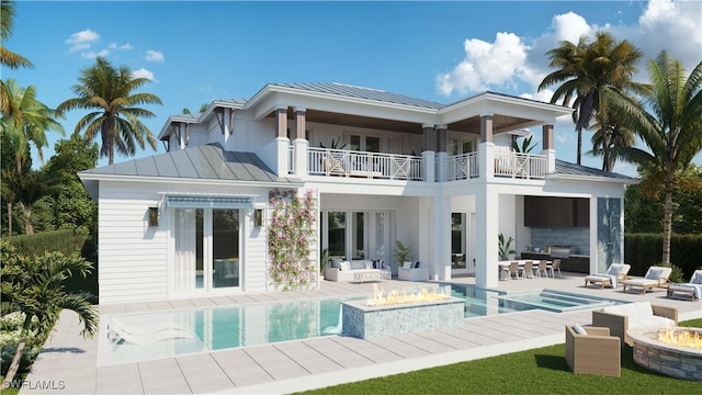 back of property featuring a swimming pool with hot tub, a patio, a balcony, and an outdoor living space with a fire pit