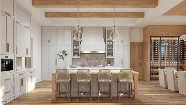 kitchen featuring a kitchen breakfast bar, light hardwood / wood-style flooring, an island with sink, pendant lighting, and custom exhaust hood