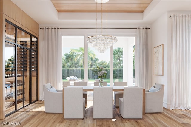 dining area with a healthy amount of sunlight, a raised ceiling, and light hardwood / wood-style flooring