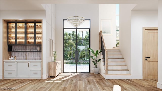 doorway to outside with light wood-type flooring and an inviting chandelier