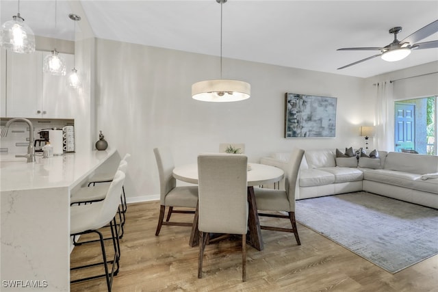 dining space with ceiling fan and light wood-type flooring