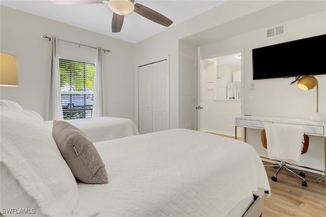 bedroom with ceiling fan, white fridge, light hardwood / wood-style flooring, and a closet