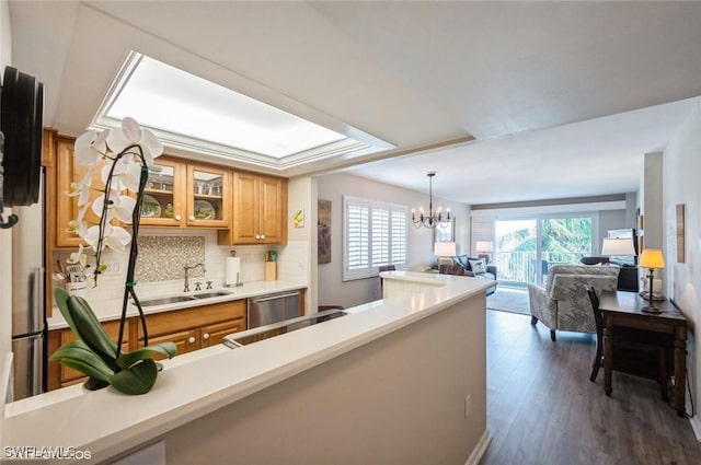 kitchen with dark wood-style flooring, open floor plan, light countertops, glass insert cabinets, and an inviting chandelier