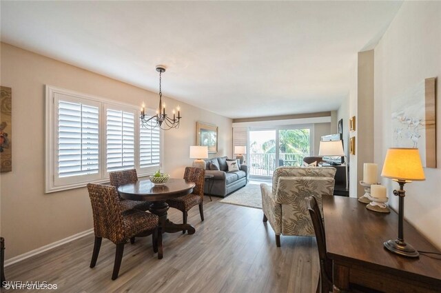 dining area with baseboards, wood finished floors, and a notable chandelier