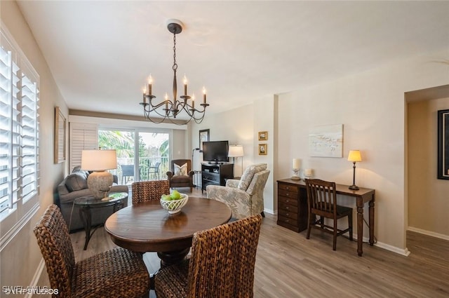 dining space with baseboards, a chandelier, and wood finished floors