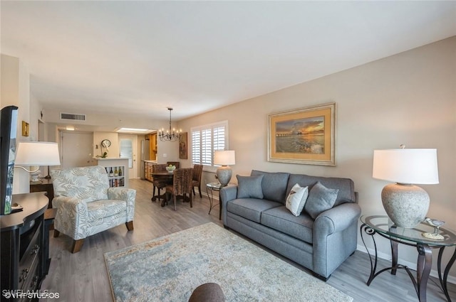 living room with an inviting chandelier and light wood-type flooring