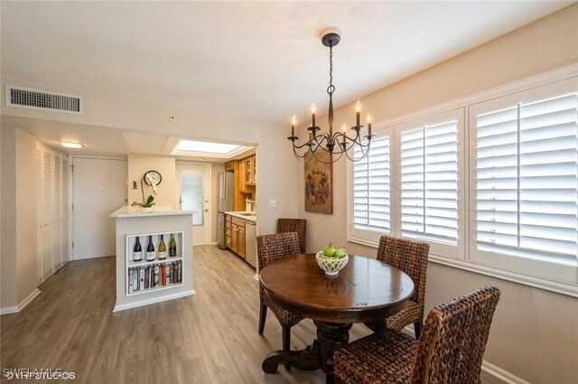 dining room with light wood-type flooring, an inviting chandelier, and visible vents