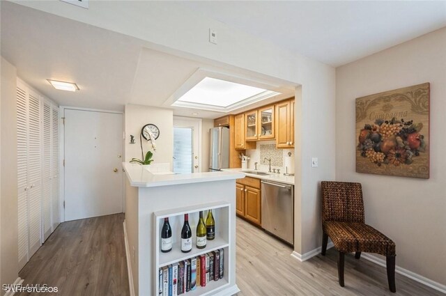 kitchen with a sink, light wood-style floors, stainless steel appliances, and light countertops