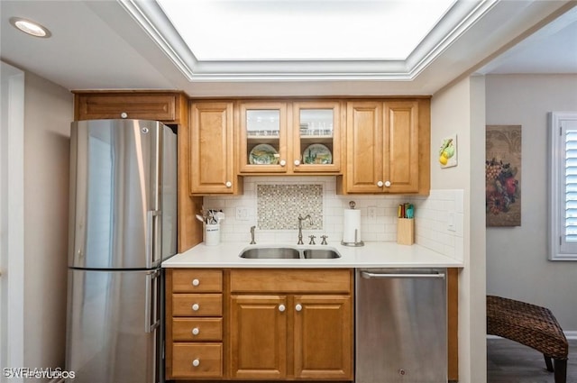 kitchen with glass insert cabinets, brown cabinets, stainless steel appliances, light countertops, and a sink