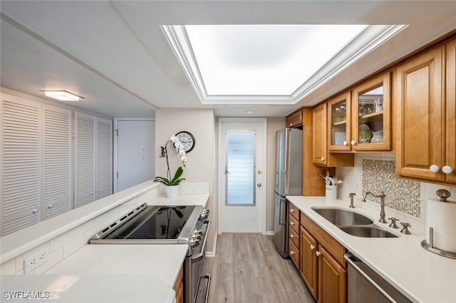 kitchen featuring glass insert cabinets, brown cabinetry, light countertops, and appliances with stainless steel finishes