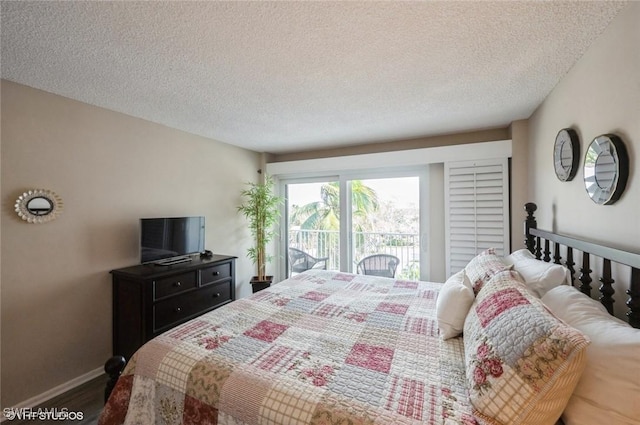 bedroom with a textured ceiling, access to outside, wood finished floors, and baseboards