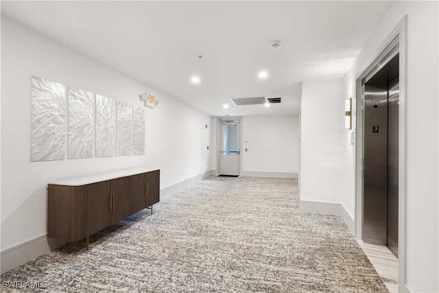 hallway with light carpet and elevator