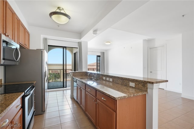 kitchen with stainless steel appliances, sink, dark stone counters, and light tile patterned floors