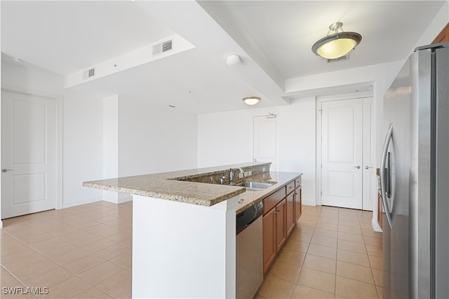 kitchen featuring light tile patterned flooring, stainless steel appliances, sink, and an island with sink