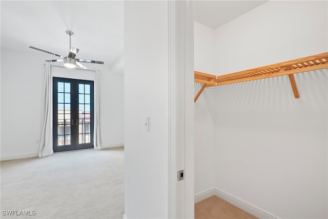 walk in closet with french doors and light colored carpet