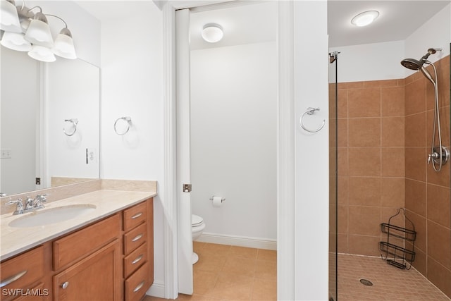 bathroom featuring vanity, a tile shower, toilet, and tile patterned floors