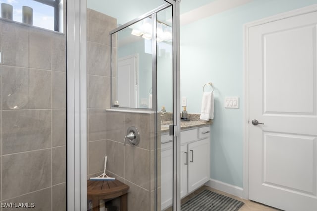 bathroom featuring a shower with door and vanity