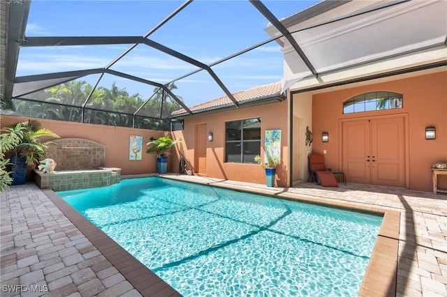 view of pool with glass enclosure and a patio area