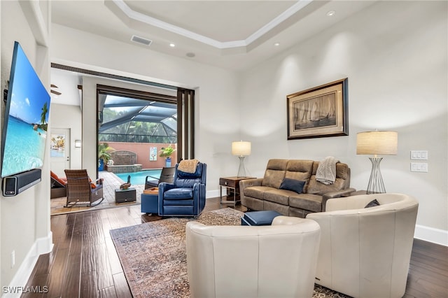 living room featuring a tray ceiling and dark hardwood / wood-style floors