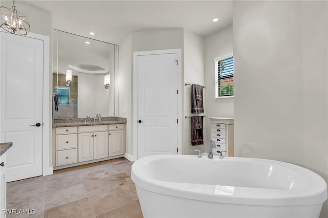 bathroom with a tub, vanity, and an inviting chandelier