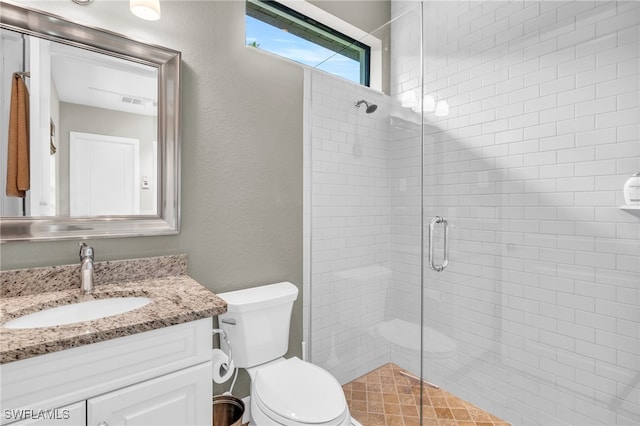 bathroom featuring vanity, a shower with door, and toilet