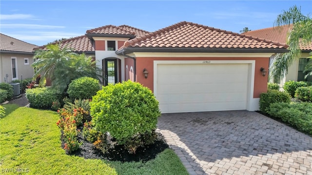 mediterranean / spanish house featuring a front yard, a garage, and central AC unit