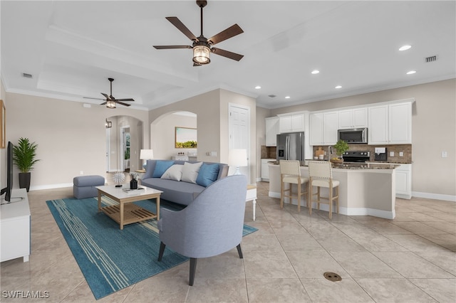 tiled living room with ornamental molding and ceiling fan