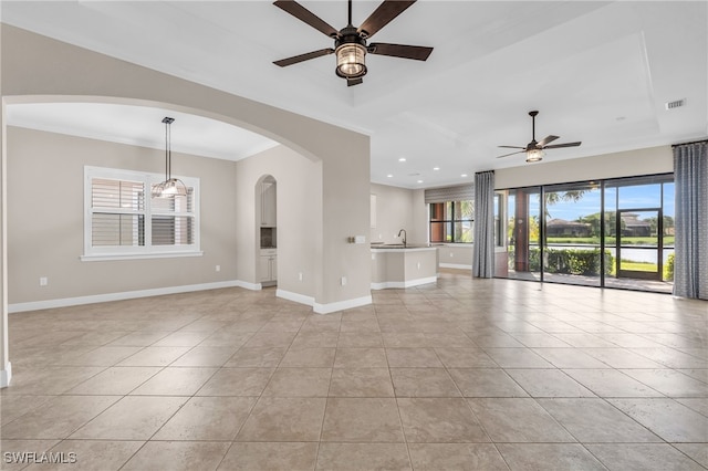 unfurnished living room featuring ceiling fan, light tile patterned floors, ornamental molding, and sink