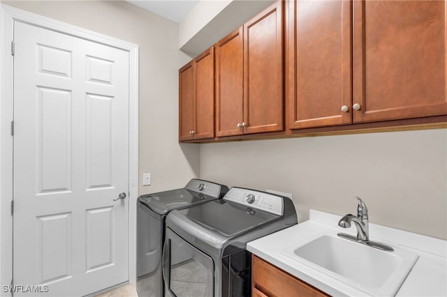 laundry area featuring light tile patterned flooring, washing machine and dryer, cabinets, and sink