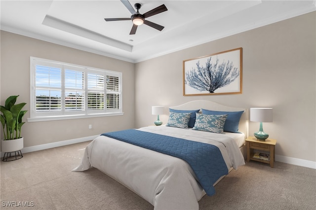 carpeted bedroom featuring crown molding, a tray ceiling, and ceiling fan