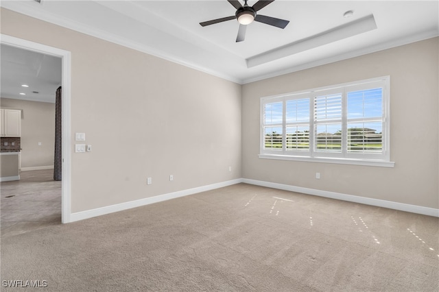 spare room with ornamental molding, ceiling fan, a tray ceiling, and light colored carpet