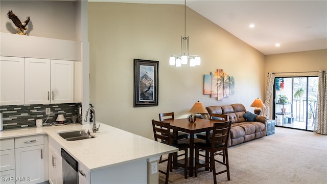 kitchen with white cabinetry, sink, backsplash, light colored carpet, and decorative light fixtures