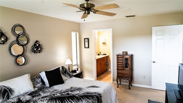 bedroom featuring ceiling fan, light colored carpet, and ensuite bath