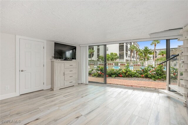 1007 Anglers Cv Unit J204, Marco Island, FL 34145 - unfurnished living room featuring a textured ceiling, light wood finished floors, and baseboards