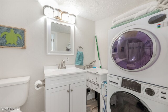 1007 Anglers Cv Unit J204, Marco Island, FL 34145 - clothes washing area featuring stacked washer / dryer, a textured ceiling, and wood finished floors