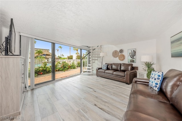1007 Anglers Cv Unit J204, Marco Island, FL 34145 - living room with floor to ceiling windows, stairway, a textured ceiling, and wood finished floors