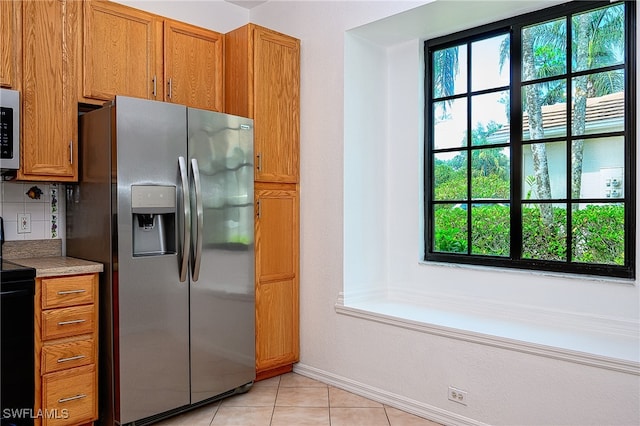 kitchen with tasteful backsplash, appliances with stainless steel finishes, and light tile patterned floors