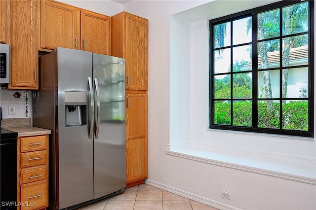 7670 Meadow Lakes Dr Unit 1501, Naples, FL 34104 - kitchen featuring brown cabinetry, decorative backsplash, light tile patterned floors, stainless steel appliances, and baseboards