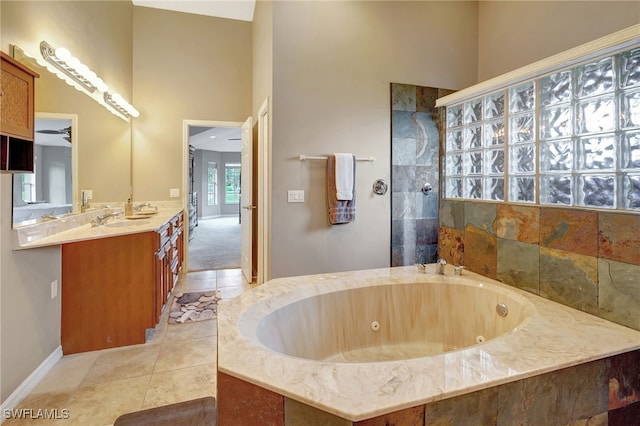 bathroom with tile patterned floors, separate shower and tub, vanity, a towering ceiling, and ceiling fan