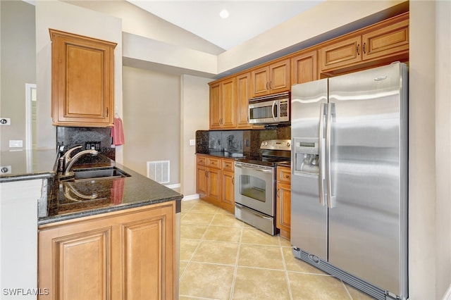 kitchen featuring tasteful backsplash, sink, stainless steel appliances, vaulted ceiling, and dark stone countertops