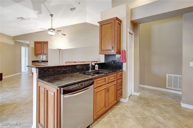 kitchen featuring lofted ceiling, light tile patterned floors, dark stone counters, dishwasher, and sink