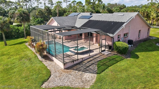 rear view of property featuring a patio, a pool with hot tub, a lanai, and a yard