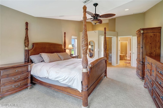 bedroom with ensuite bath, light colored carpet, a towering ceiling, and ceiling fan