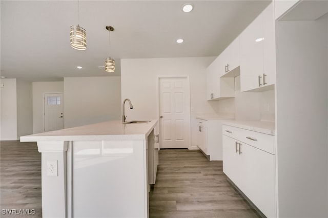 kitchen with sink, wood-type flooring, a center island with sink, white cabinetry, and hanging light fixtures